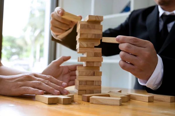 Businessmen picking wood blocks to fill the missing wood blocks