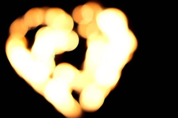 Defocused bokeh lights of the burning heart. Fire in the night. Bright light of burning heart. symbol of love. Burning heart close-up with flames, amazing fire show at night at festival or wedding party. fire show performance and entertainment.