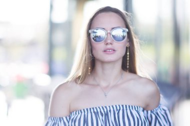 Soğuk renklerde ayna güneş gözlüklü bir kız moda portre. Kız ışık bokeh arka plan üzerinde
