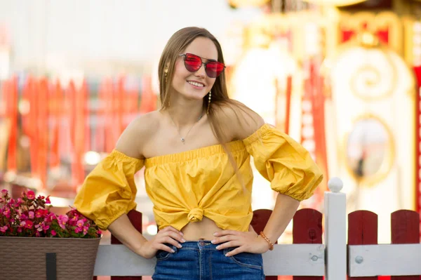 漂亮的年轻女子穿着一件黄色的上衣 红色的太阳镜高兴得笑了 度假理念 — 图库照片