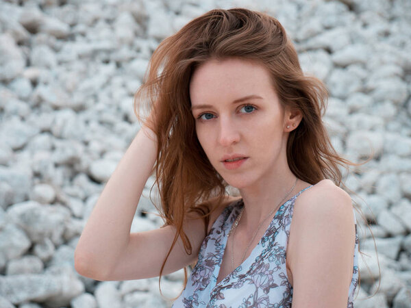 Portrait of a young beautiful girl on a background of white stones