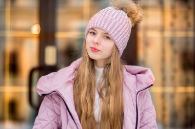 Bir kız bir pembe sıcak ceket ve şapkayla