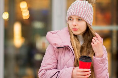 Bir kız bir pembe sıcak ceket ve şapkayla