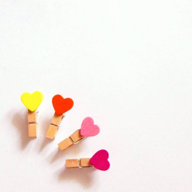 Beyaz bir arka planda renkli kalpler ile küçük clothespins. Tatlı aşk. Boşluk Kopyala.