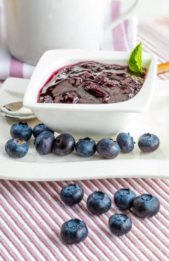 Lezzetli reçel taze yaban mersini. Bir arka planda beyaz çizgili ve pembe Garnet.