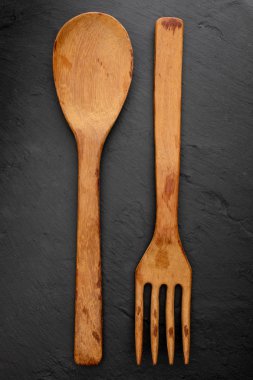Tahta kaşık ve çatal dokulu siyah kara tahta arka plan üzerinde. Metninizi buraya eklemek için alan. Restoranlar için mektup. (Gıda kavramı kaşık, tencere).