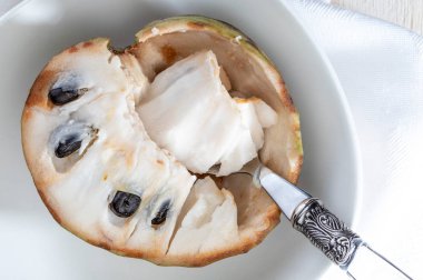 Olgun Cherimoyalara yakın çekim. Açık meyve, nugget ve hafif arka planda kaşık.