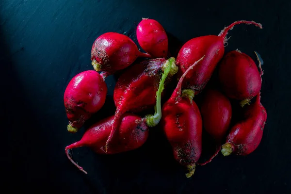 Ecological radishes (red radishes - rabanites) of intense red color. Close-up on black background.