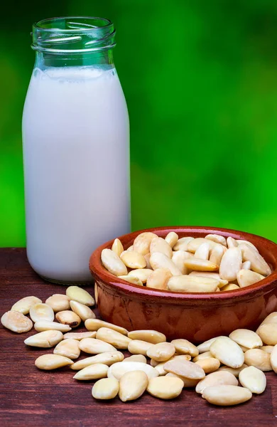 Almond milk in glass bottle. Includes peeled almonds. On green n