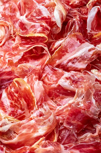 Rebanadas apetitosas Jamón ibérico en primer plano como textura. Carne cruda que se convierte en un artículo de alta cocina y lujo gastronómico, a través de un proceso de salazón cruda y curado natural . —  Fotos de Stock