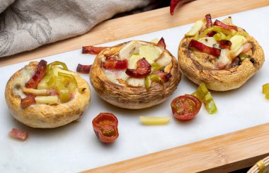 Lezzetli mantar (champignon, ayak kesim, Agaricus Bisporus) pişmiş ve dolması (pastırma, domates, sarımsak, biber, ...). Yakın çekim.