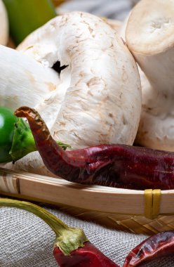 Sepet mantar (champignon, kesilmiş ayak, Agaricus Bisporus) çiğ (pişmemiş). Çeşitli malzemelerle (zeytinyağı, sarımsak ve biber). Ahşap arka plan ve ev görünümü.