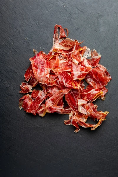 Apetitivos trozos de jamón ibérico en primer plano. Aceite de oliva. Fondo negro. Espacio para insertar el texto . —  Fotos de Stock