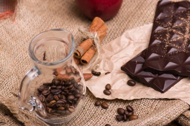 Siyah kumaş üzerine çikolata. Fındık, tarçın, kırmızı elma, kahve.