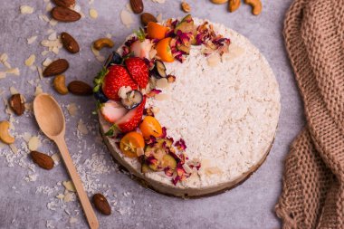 Çilek, portakal, fındık ile parlak pasta. Tahta kaşık ve bez ile tablo.