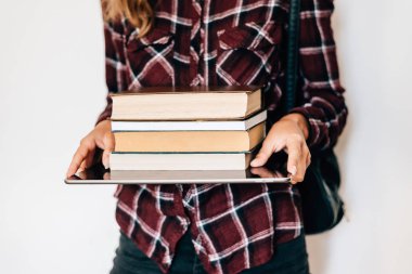 Bir tablet ve kitapların bir yığınına tutan bir kız elleri. Bilgi kavramı.