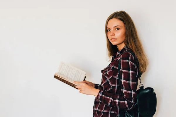 彼女の手とバックパック コピー スペースと白い背景で読む本を持つ少女 — ストック写真