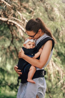 Küçük bebek kız ve annesi babywearing dışında yürüyüş ergo taşıyıcı kavramı