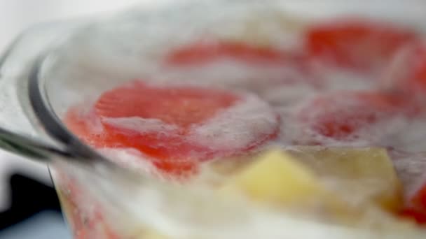 Mouvement lent du bouillon de soupe bouillante avec carotte et pomme de terre dans une casserole en verre — Video