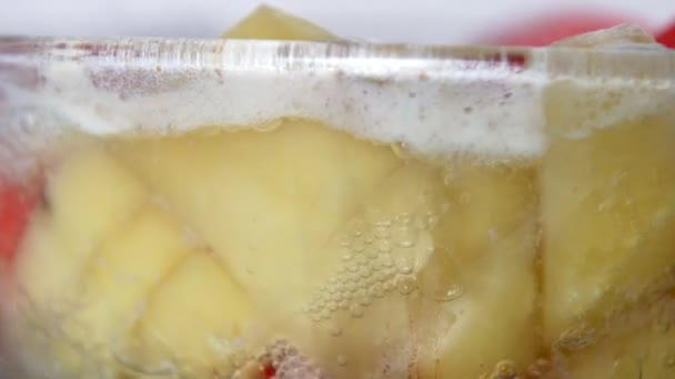 Mouvement lent du bouillon de soupe bouillante avec carotte et pomme de terre dans une casserole en verre — Video