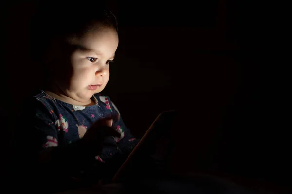 Baby toddler with face lit from phone screen at night, genration z early learning cartoons