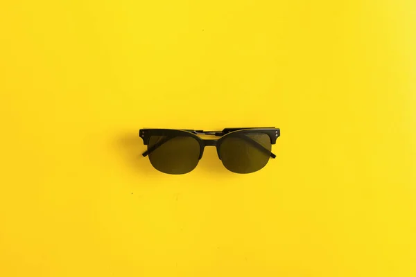 Occhiali da sole neri su sfondo giallo, concetto di protezione UV estate per gli occhi — Foto Stock