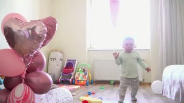 Evde ballons ile küçük bebek kız doğum gününde ilk adımları yürüyor, bir yıl