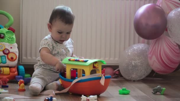 Baby peuter speelt met kunststof groot schip op haar verjaardag met roze ballons — Stockvideo