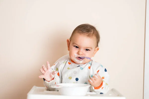 En liten bebis som äter sin middag och ställer till det — Stockfoto