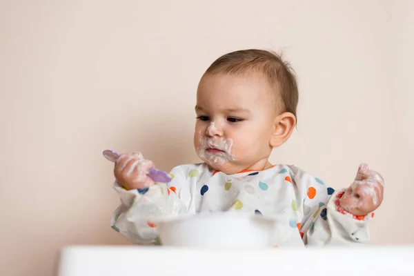 En liten bebis som äter sin middag och ställer till det — Stockfoto