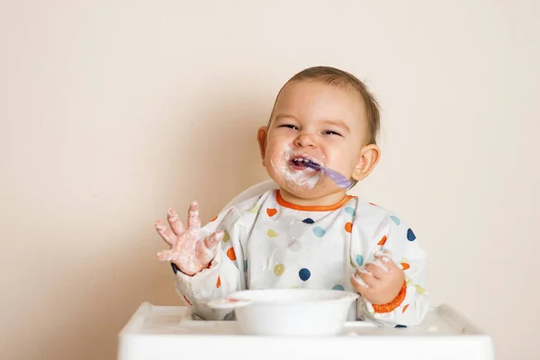 Küçük bir bebek yemeğini yiyor ve ortalığı dağıtıyor.