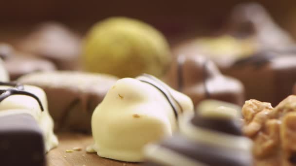 Dulces de chocolate hechos a mano que caen sobre fondo de madera, dulces sabrosos en cámara lenta uhd — Vídeos de Stock