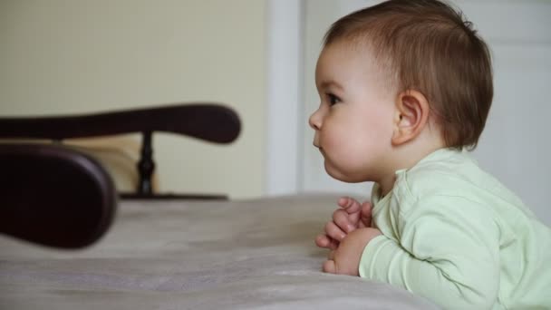 Bebé pequeño de pie cerca del sofá y viendo dibujos animados calma y concentrado en casa, tiempo tranquilo — Vídeos de Stock