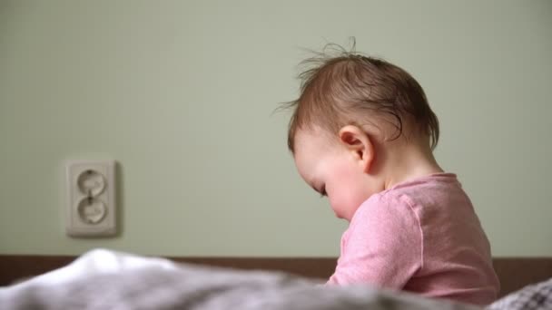 Souriant petite fille avec de gros yeux sur le lit en regardant la caméra — Video