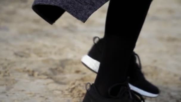 Fermez les jambes dans des baskets élégantes marchant sur le sable, au ralenti, steadicam shot. Chaussures concept — Video