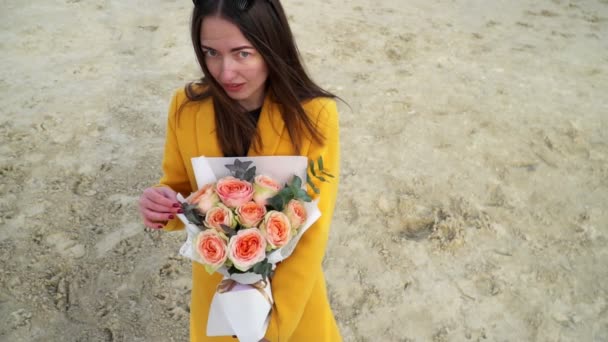 Fille dansant joyeusement avec bouquet de roses pombastique en manteau jaune, gros plan — Video