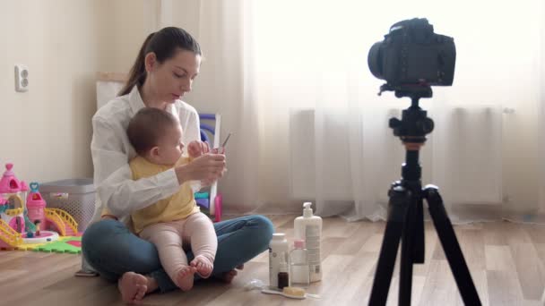 Молодая мама с маленьким мальчиком записывает видео на камеру и рассказывает о семье и детстве — стоковое видео