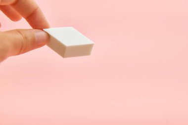 Pembe arka plan üzerinde ellerde dikdörtgen kozmetik beyaz sünger, kopya alanı, güzellik