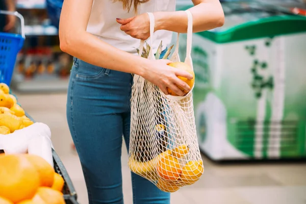 Kobieta z siatkową torbą pełną świeżych warzyw zakupy w sklepie, koncepcja zero odpadów — Zdjęcie stockowe