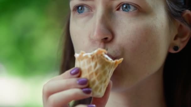Közelkép portré nyári háttérrel. Fiatal nő eszik fagylaltot — Stock videók