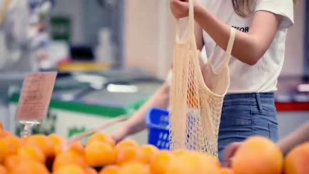 Chica bonita mujer recogiendo verduras y frutas en supernarket en bolsa de compras orgánica de malla, cero residuos, respetuoso del medio ambiente — Vídeos de Stock