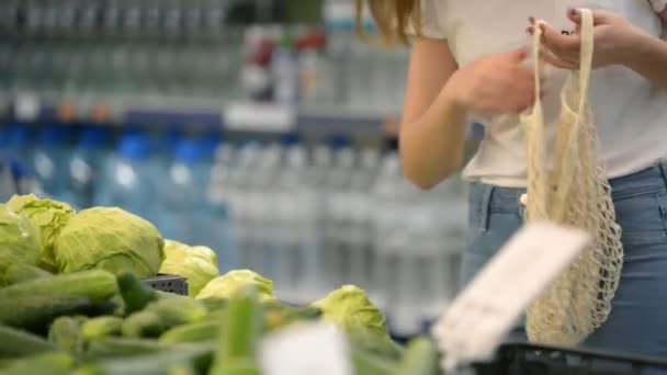 Mulher bonita colhendo legumes e frutas em supernarket em malha saco de compras orgânico, zero resíduos, eco friendly — Vídeo de Stock