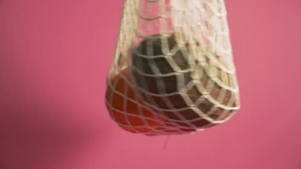 Fruits and vegetables in mesh bag, alternative to plastic shopping bags on pink background 4k — Stock Video