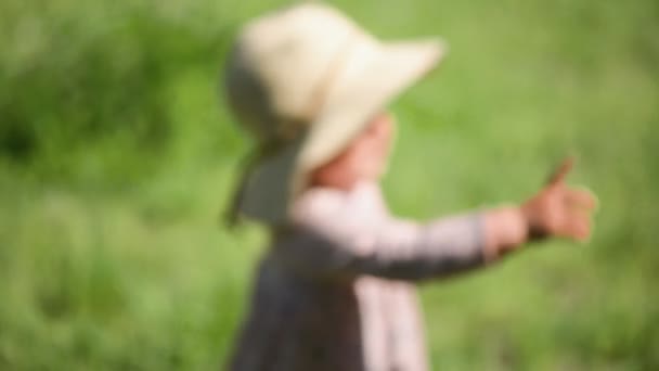 Baby meisje staande op het gras in stro hoed en jurk, grappige buik, warm weer — Stockvideo