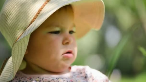 女婴触摸树叶在草帽和礼服，夏天的一天 — 图库视频影像