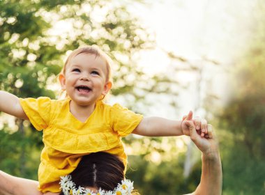 Kadın sevimli çocuk kız bebek ile eğleniyor. Doğada piggyback dışında. Anneler Günü