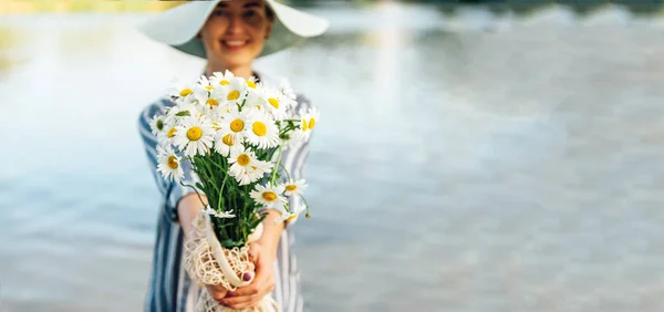 Heřmánkový Buket v dívkách rukou na pozadí řeky. "Šťastný květinář." Kalmingový čaj — Stock fotografie