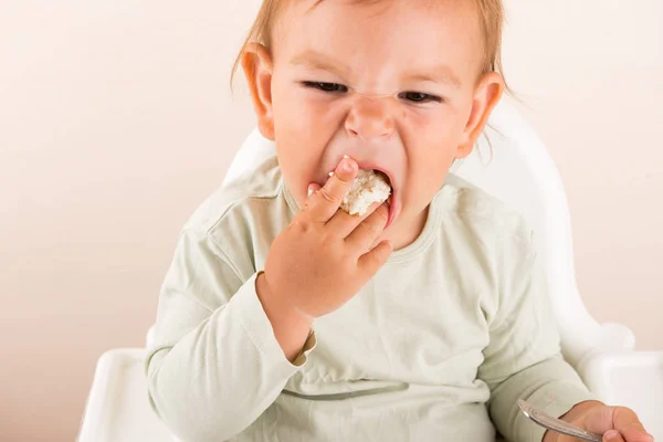 A criança bebê come comida com os dedos. Cara engraçada. Espaço de cópia — Fotografia de Stock