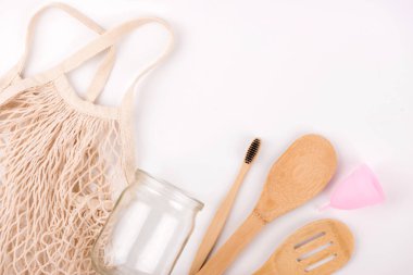 Sıfır atık çevre dostu düz yatıyordu. Beyaz arka plan. Örgü alışveriş çantası, adet fincan, bambu diş fırçası