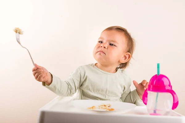 Baby toddler eating pancakes with fork. Isolated. Copy space